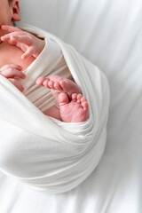Peaceful Newborn Baby Wrapped in White Swaddle with Tiny Feet and Hands on White Background