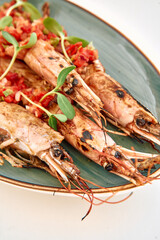 Grilled king prawns with salsa garnish on ceramic plate