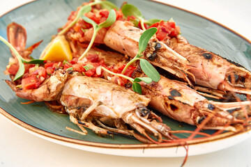 Grilled langoustines topped with tomato salsa and microgreens on ceramic plate