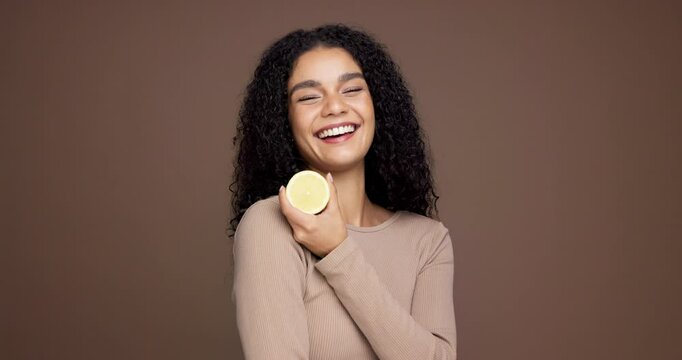 Happy woman, face and diet with lemon in studio for citrus acid or detox on a brown background. Portrait, female person or model with smile or natural organic fruit for vitamin C or health on space