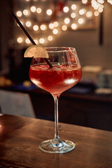 Festive cocktail with lemon garnish and straw on wooden bar counter