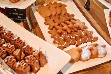 Festive gingerbread cookies on white plate with chocolate cake assortment