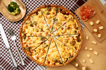 Savory salmon broccoli quiche with cheese topping on checkered tablecloth