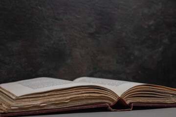 Antique open book with deckled edges viewed at a slight angle, resting on textured surface with...