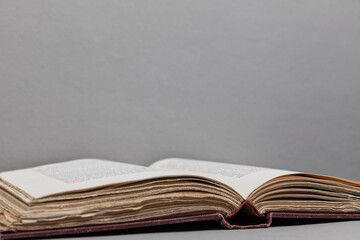 Antique open book with deckled edges viewed at a slight angle, lying flat against a textured gray...