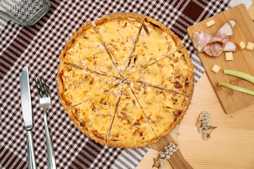 Delicious quiche on checkered cloth with sliced ham cheese garnish