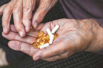 Close-up of elderly woman's hands holding capsules and pills, showing daily vitamins and supplements, concept of health and aging.