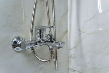 In a bathroom, there is a shower head that has a flexible hose connected to it, allowing for...