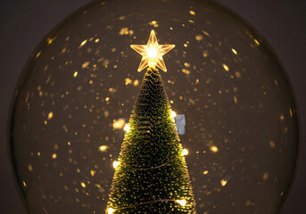 Snow globe with christmas tree and star made of lights and soft falling snow in the background - christmas concept