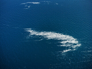 Aerial shot of white foam and streaks on ocean surface, suggesting chemical or industrial sea...