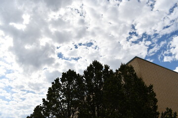 Brick shopping mall. Upward angle pointing at the sky. Cloudy sky with several trees.