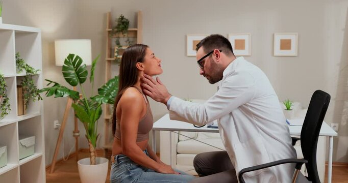 Doctor examining patient's neck in medical office during consultation