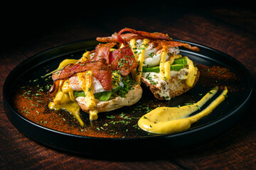 Pan tostado con tocino crujiente, huevos, aguacate, salsa de queso y espolvoreado con perejil