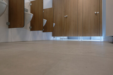 A modern public men's restroom with urinals and two toilets in cubicles photographed from below