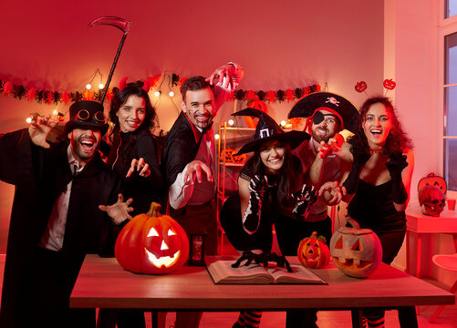Group portrait of friends in costume celebrating halloween during night party with pumpkin, showcasing togetherness in a festive setting with focus on holiday fun and lively atmosphere.