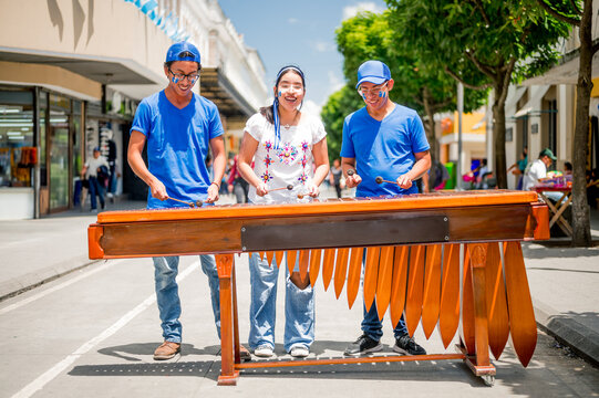 Young Latinos play their country's native instrument. Latino boys play the marimba in the middle of a pedestrian street.