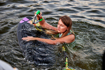Woman holding a rope on a wakesurf board in water