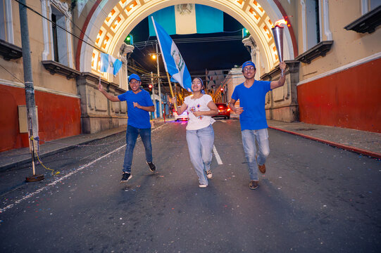 Young Guatemalans run down a street in the Historic Center, carrying flags and a torch, as they celebrate Independence Day.