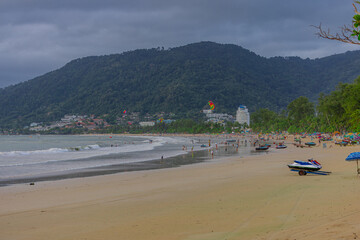 Fototapeta premium Patong Beach in the beautiful island of Phuket Thailand. Lovely colours of the sky at sunset and the turquoise blue waters of the Andaman sea people parasailing and swimming