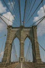 Obraz premium Brooklyn Bridge in New York City Viewed from Pedestrian Path – Iconic Suspension Bridge Architecture with Steel Cables and Blue Sky