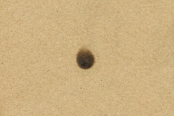 Dark oil stain on a brown kraft paper texture. Concept of leak, dirt, or grease spot. Grunge abstract background for design.