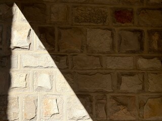 Ancient stone wall with triangular shadow. 