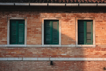 Fototapeta premium Red brick building featuring vibrant green windows isolated