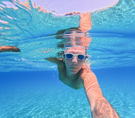 Man swimming underwater in the Mediterranean sea off Sicilian coast. The man is forty years old, of...