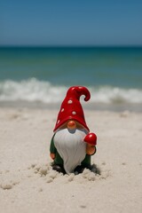 Obraz premium Whimsical Gnome on Sandy Beach with Ocean Backdrop