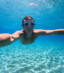 Man swimming underwater in the Mediterranean sea off Sicilian coast. The man is forty years old, of...