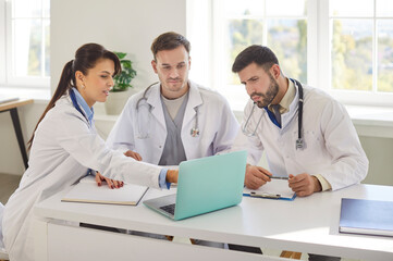 Group of a concentrated doctors and nurses working together in a clinic office during a meeting,...