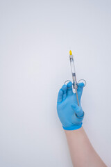 A hand is holding a syringe that has a yellow tip, situated within a medical setting