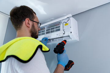 Professional technician performs routine maintenance on a modern air conditioning unit mounted on a...