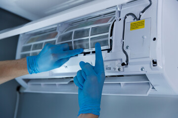 Professional HVAC Technician Performing Air Conditioner Maintenance with Blue Gloves for Improved...