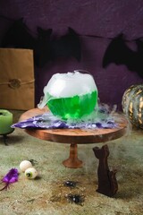 Halloween concept, boiling magical green potion in round glass pot with white smoke on wooden stand