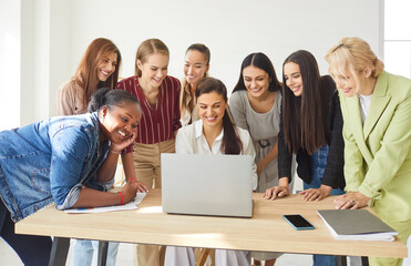 Fototapeta premium Group of women colleagues collaborates in an office meeting, working together with a laptop on business tasks, showcasing teamwork, corporate team communication, and professional goals.
