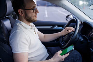 A Focused Driver Engaged with His Smartphone While Seated in the Car, Portraying a Blend of Modern...