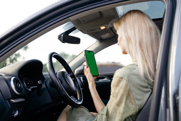 A Young Woman in a Car Holding a Smartphone with a Green Screen Background While Relaxing in the...