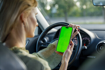 A Focused Driver Holding a Smartphone with a Bright Green Screen While Driving, Illustrating the...