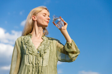 Enjoying Nature and Hydration: A Woman Revels in the Beauty of the Outdoors While Drinking...