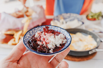 Cottage cheese with cherry jam served in a small bowl during a rich breakfast with scrambled eggs and bread
