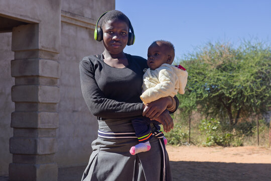 africa village, single african teenager mother holding child wearing school uniform, teenage girls pregnancy back to school, sexual education young age