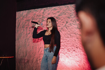 Obraz premium beautiful young Latina woman with a microphone in karaoke or singing
