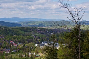 Golden-hued valley town basking in gentle light, embraced by rugged hills and patchy clouds. Bare...