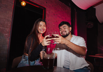 LGBT couple friends sitting and drinking beer in a bar happily