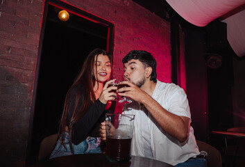 LGBT couple friends sitting and drinking beer in a bar happily