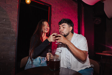 LGBT couple friends sitting and drinking beer in a bar happily