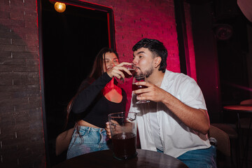 LGBT couple friends sitting and drinking beer in a bar happily