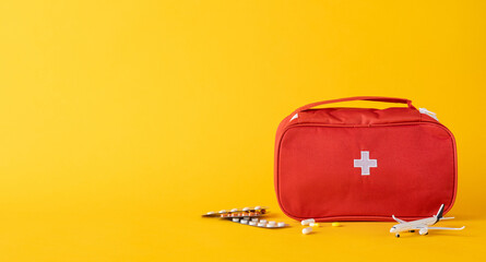 Medical first aid kit with pills and equipment arranged on a vibrant yellow surface