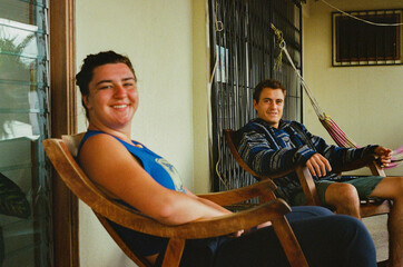 Two friends enjoy a peaceful moment seated in wooden rocking chairs on a patio.